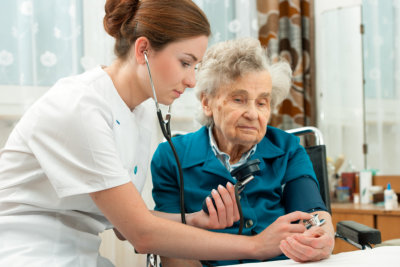 Female nurse measuring blood pressure of senior woman